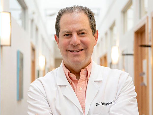 Profile of Dr. Joel Schlessinger in lab coat standing in a hallway inside Schlessinger MD office