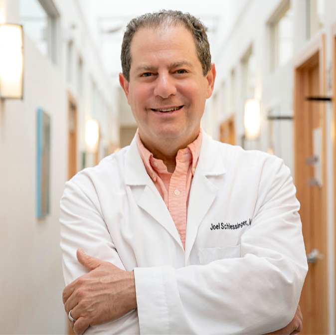 Profile of Dr. Joel Schlessinger in lab coat standing in a hallway inside Schlessinger MD office