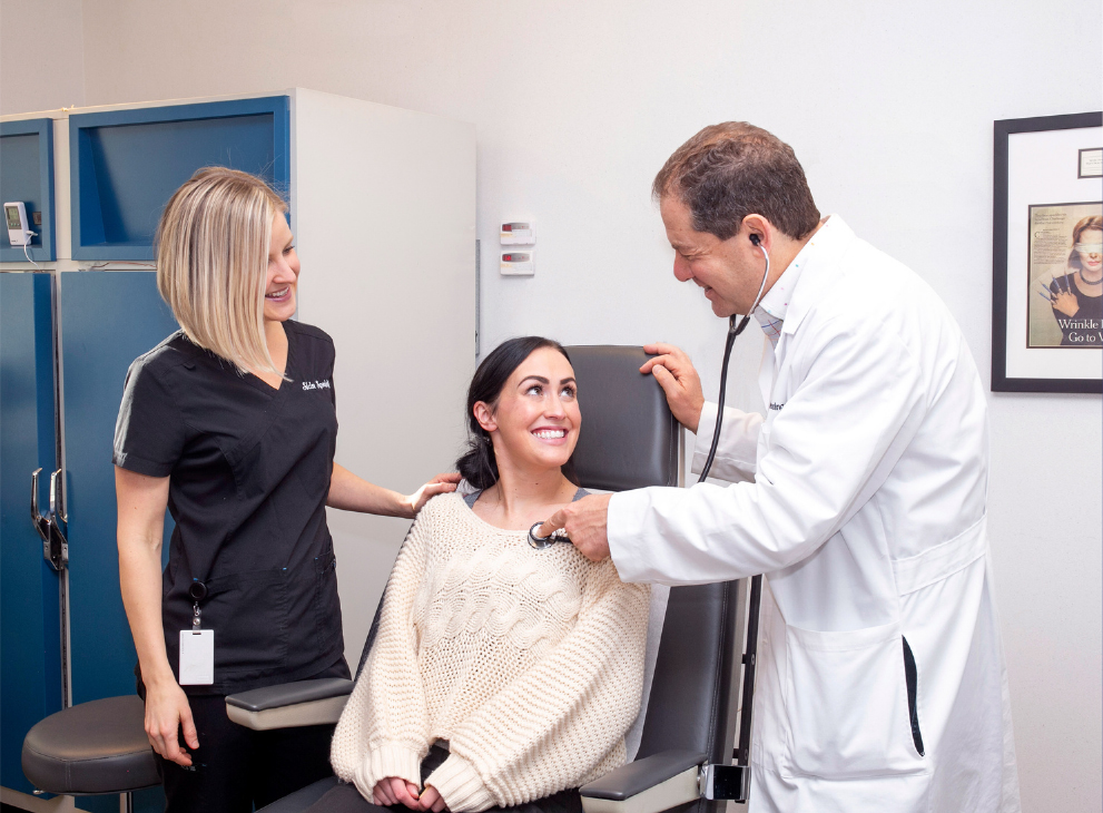 Dr. Joel Schlessinger using a stethoscope on a patient