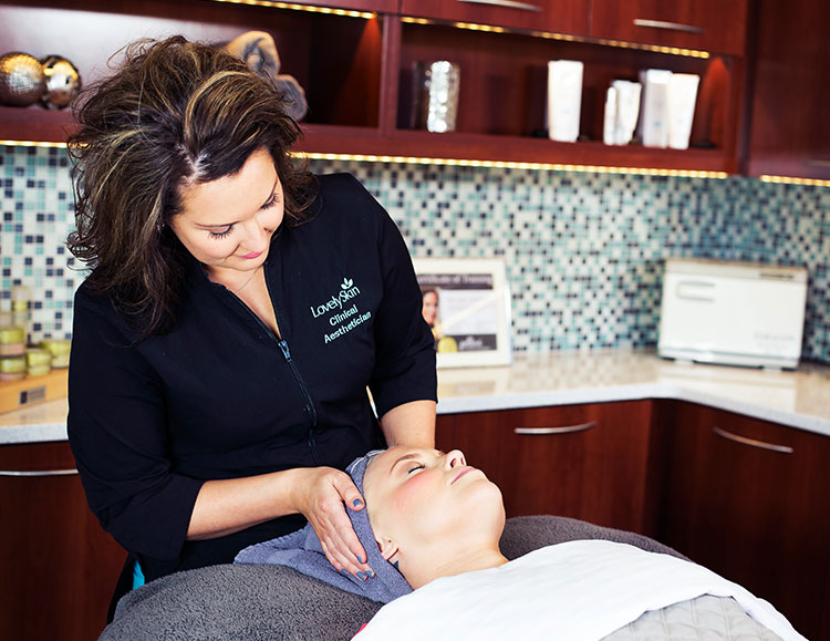 LovelySkin Spa Aesthetician giving a light skin toned woman a facial