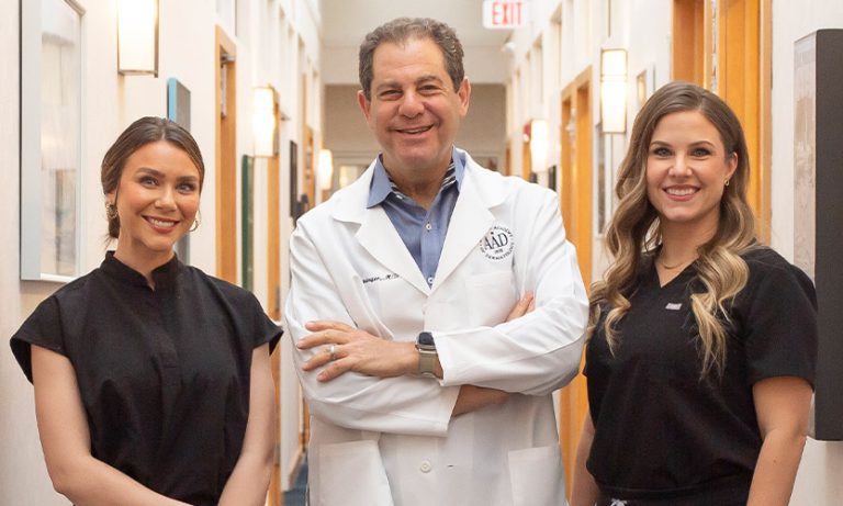 Dr. Joel Schlessinger standing next to two patient coordinators